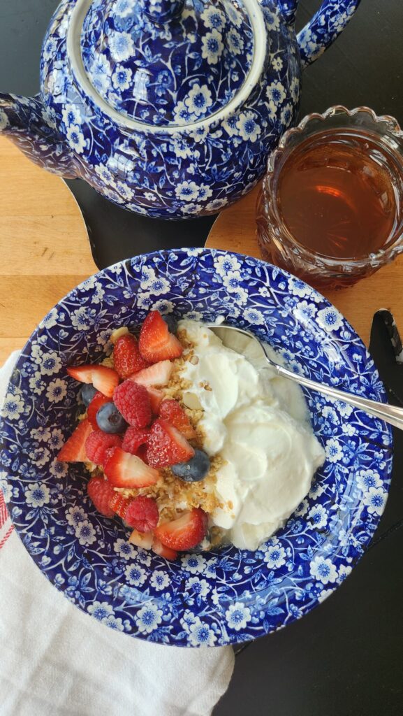 blue and whit calico bowl with yogurt and granola drizzled with honey