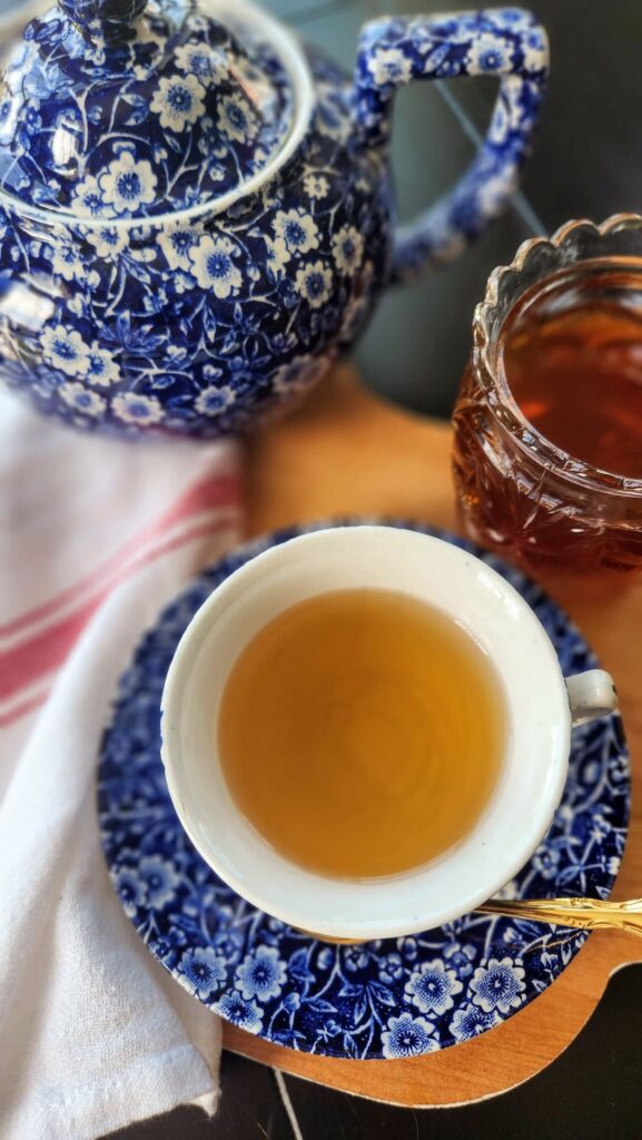 blue calico teacup and saucer with tea and crystal honey pot on the side of cup