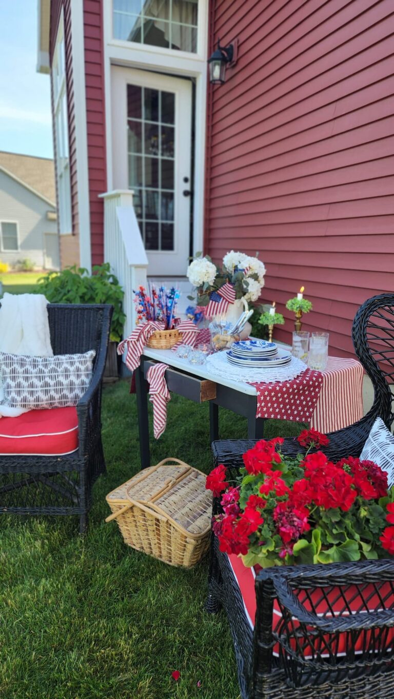 outdoor table decorated with red geraniums, patriot decor and flags