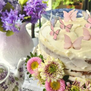 close up of decorated cake with edible butterflies and real flowers around it