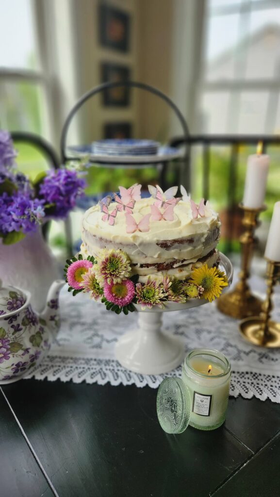 cake on table decorated with real flowers and edible butterflies on the top