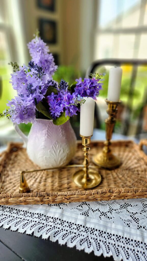 wicker tray with vintage pitcher and lavender flowers in it on dining room table