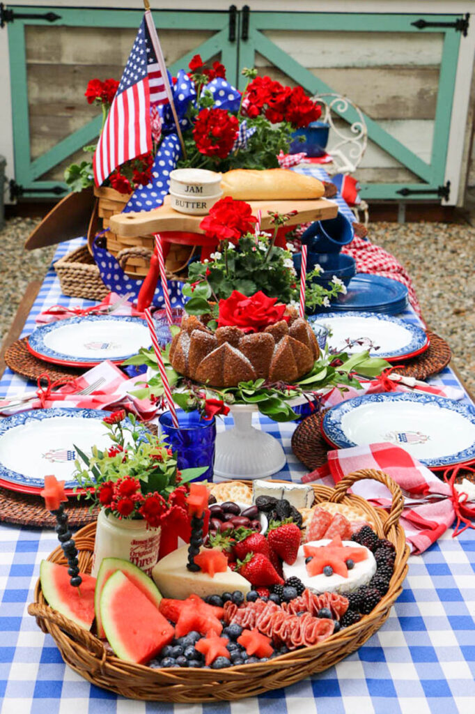 outdoor memorial day table with a wicker tray filled with watermelon, berries and cheese.