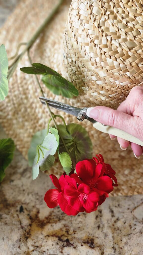 ladies hand clipping faux flowers for a decorative hat wreath