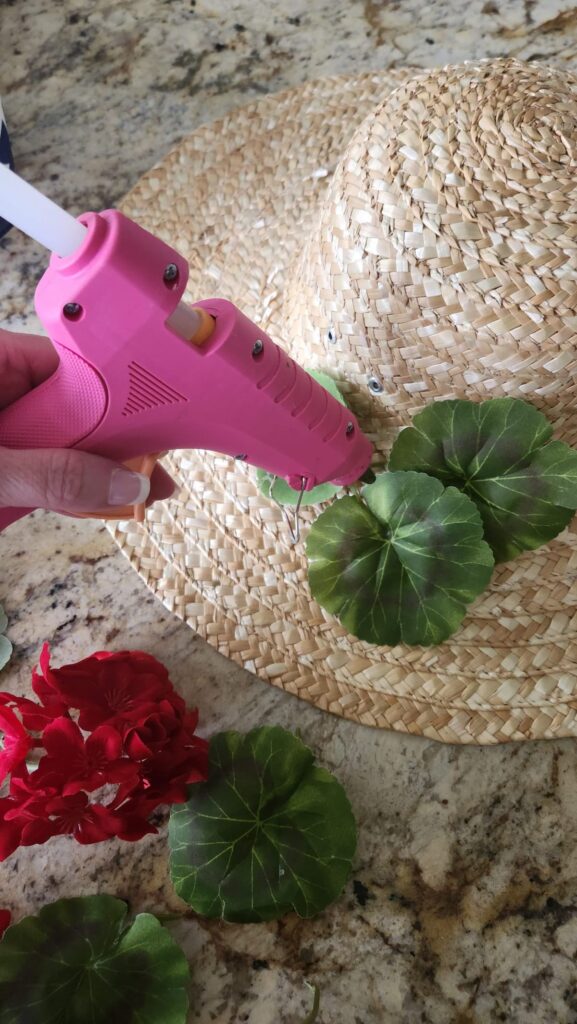 glue gun attaching greenery to straw hat