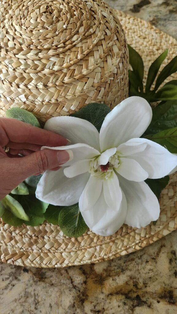 white magnolia flower being added to straw hat wreath