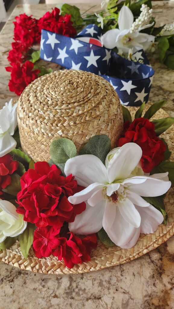 adding red geraniums to straw hat wreath