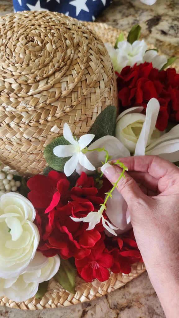 adding tiny white florals to straw hat wreath