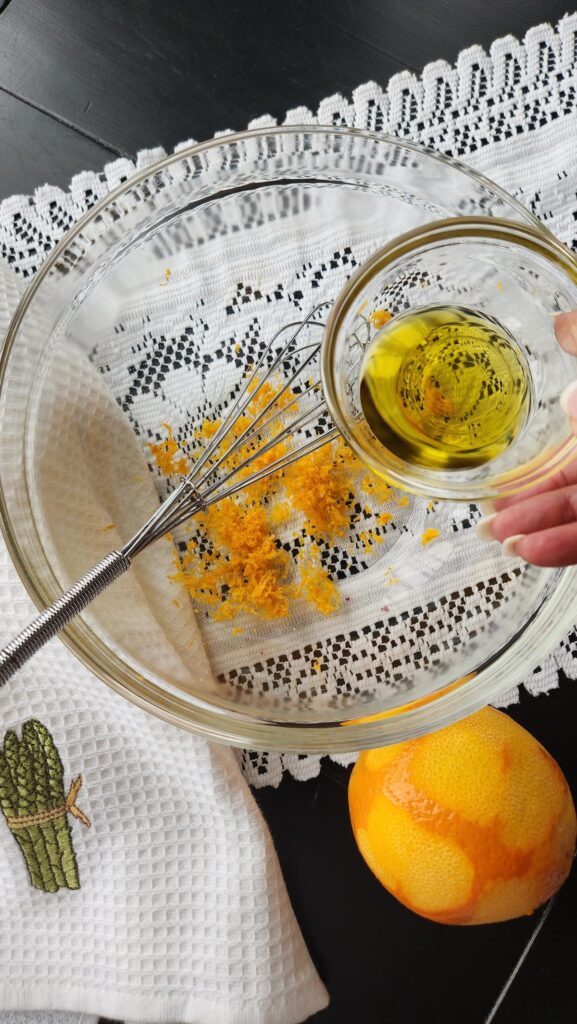 olive oil in glass bowl being added to orange zest 