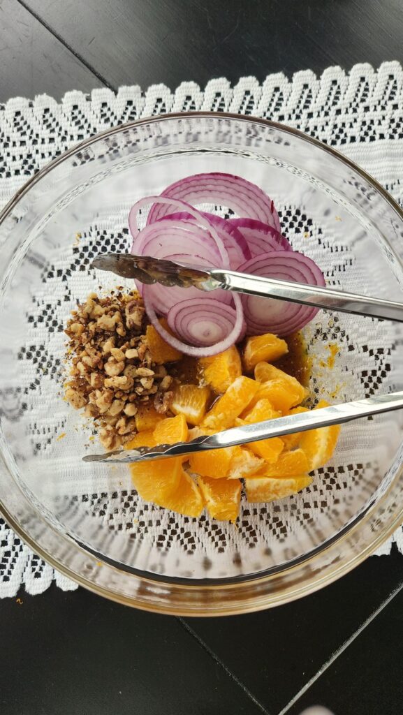 glass mixing bowl with orange segments, walnuts and red onion slices