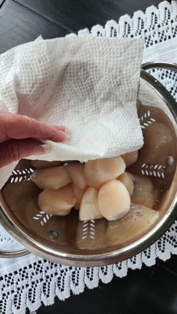 scallops being patted dry with paper towel