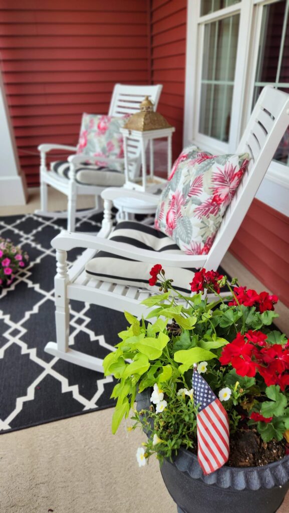 white rocking chairs with black and white cushions and flowered pillows