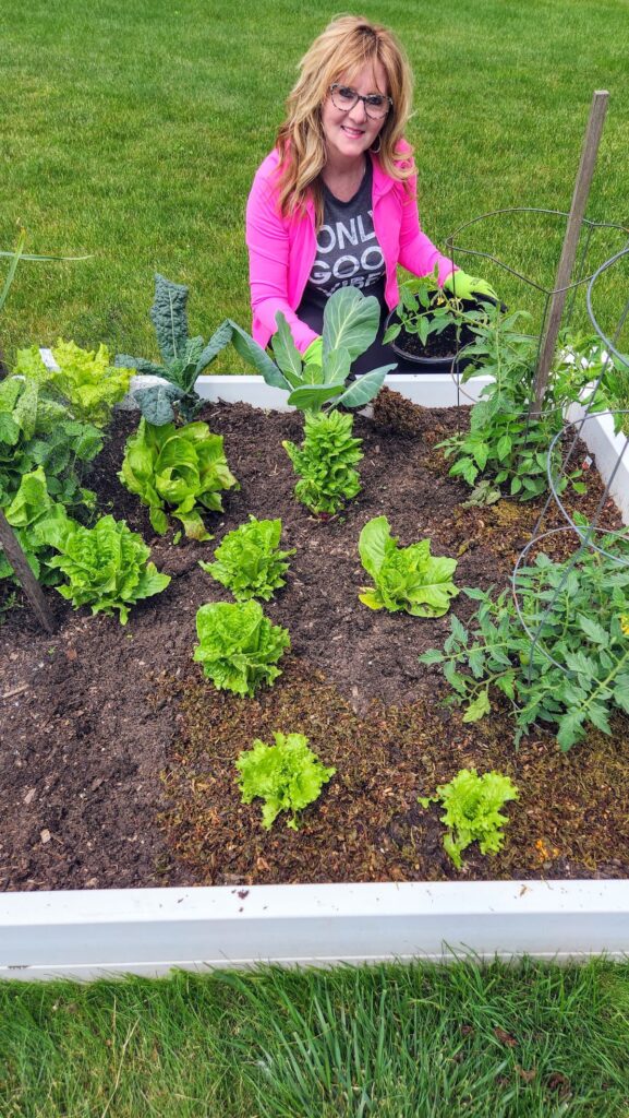 lady kneeling by garden bed putting tea leaves around the base of the plants