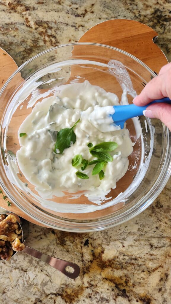 overhead photo of glass bowl with goat cheese and sour cream being mixed