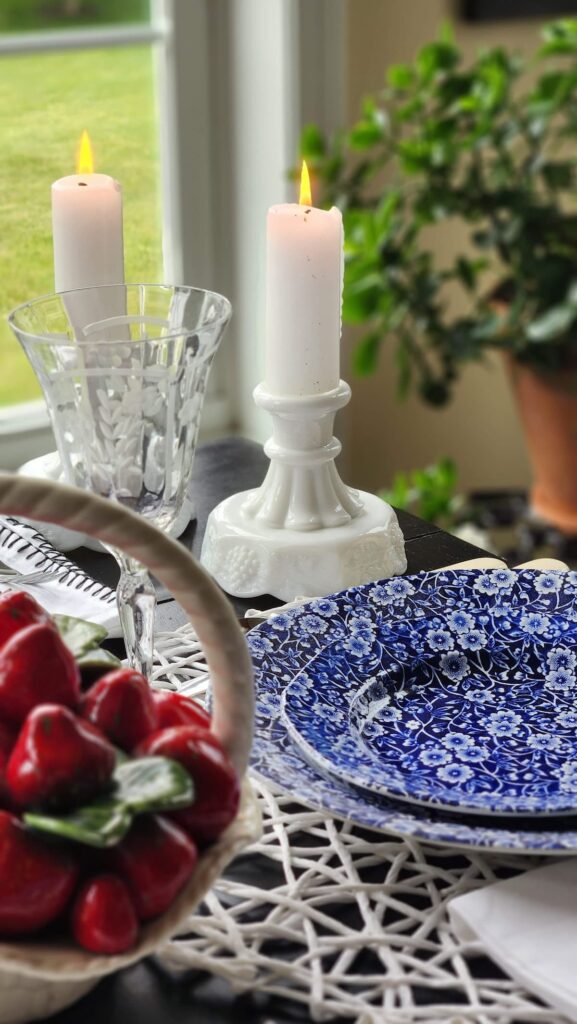 white milk glass candlestick holders with blue chintz dishes on table