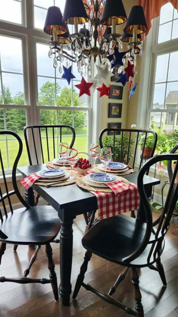 patriotic table with red and white checked table runner and felt stars strung on chandelier