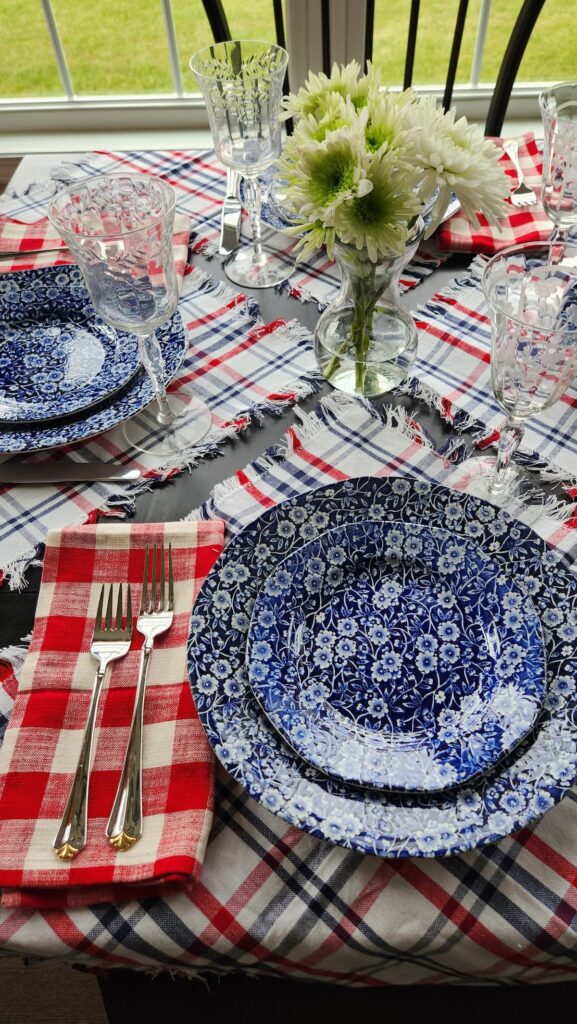 plaid napkins on table used as a placemat with blue chiintz dishes and red checked napkin 