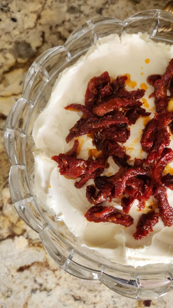 overhead view of sundried tomatoes being spread onto goat cheese
