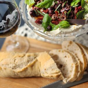 sliced french bread with sundried tomato and goat cheese dip overhead photo