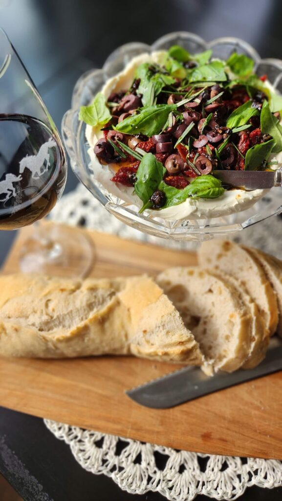 sliced french bread with sundried tomato and goat cheese dip overhead photo