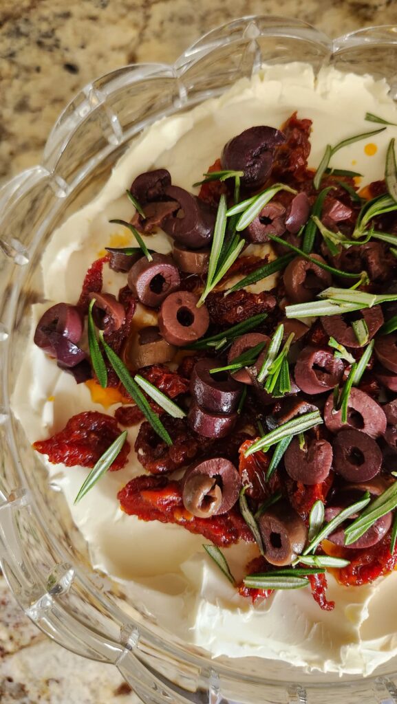 overhead view of goat cheese spread with kalamata olives sundried tomatoes and rosemary