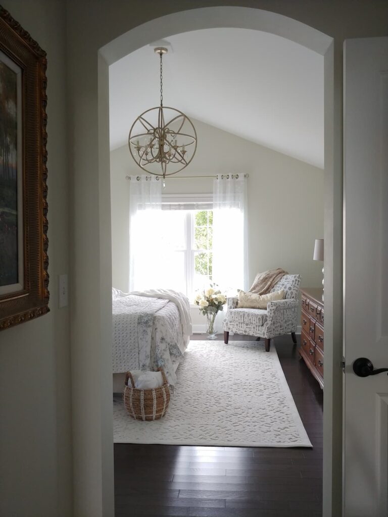 view into bedroom with chair, rug and end of bed showing