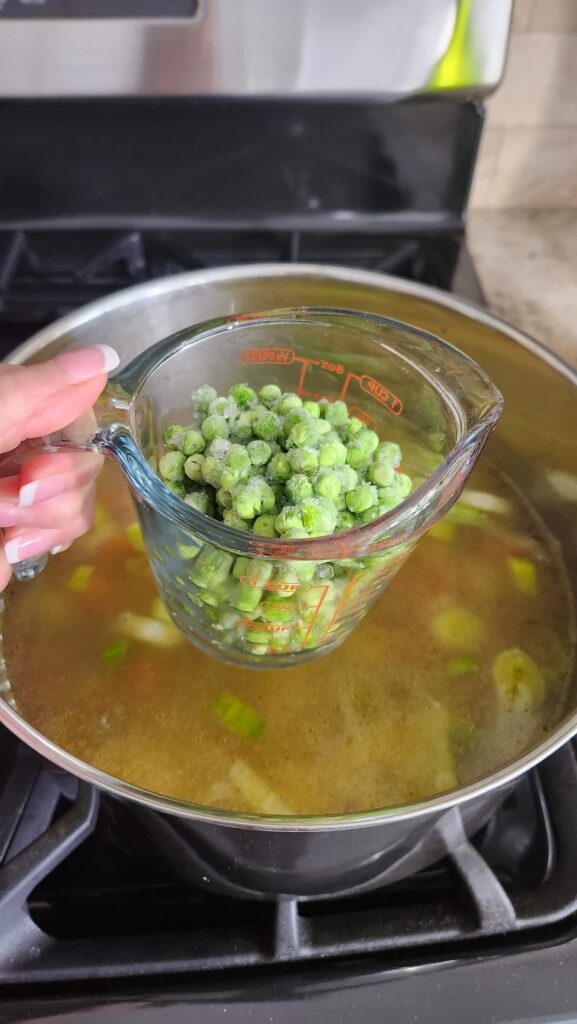 peas in measure cup being added to soup