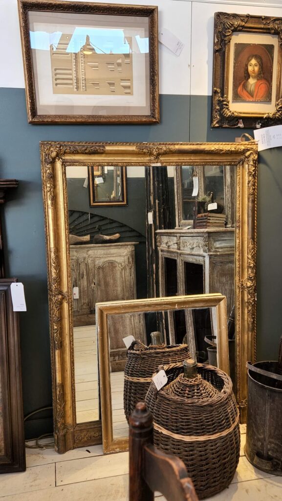gold leaf mirrors leaning against a wall 