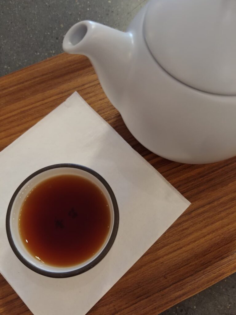 overhead of tea in small cup with white tea pot next to cup