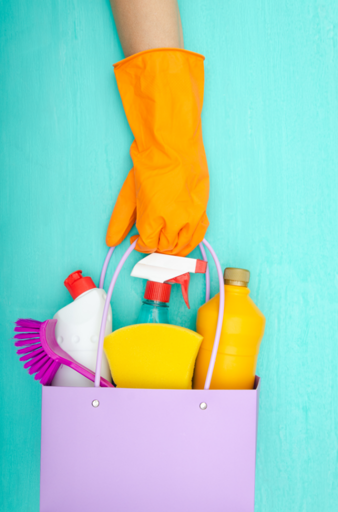 bucket of cleaning tools with hand in orange glove holding the bucket