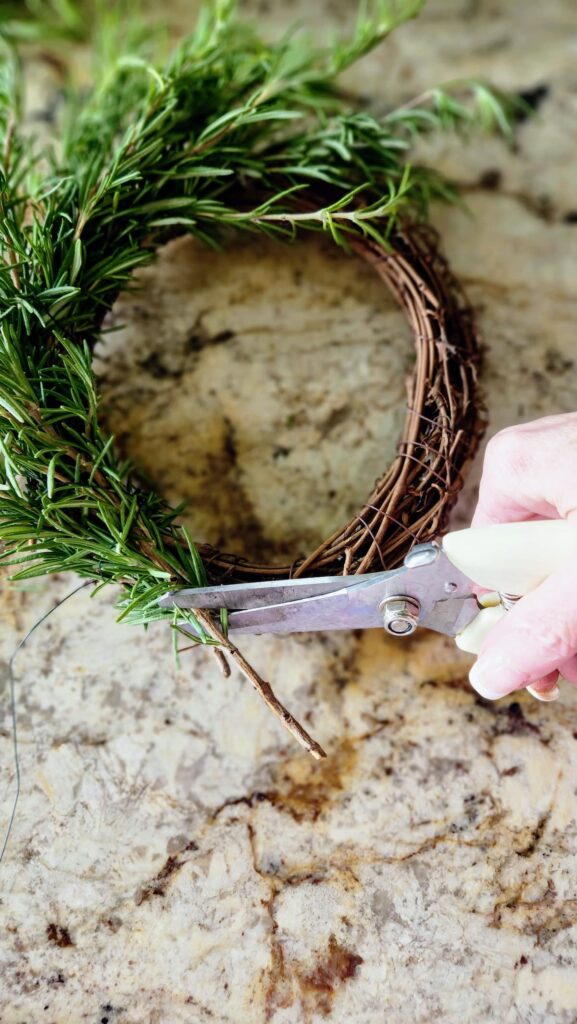 using wire cutters, clipping the ends of the rosemary sprigs that are too long