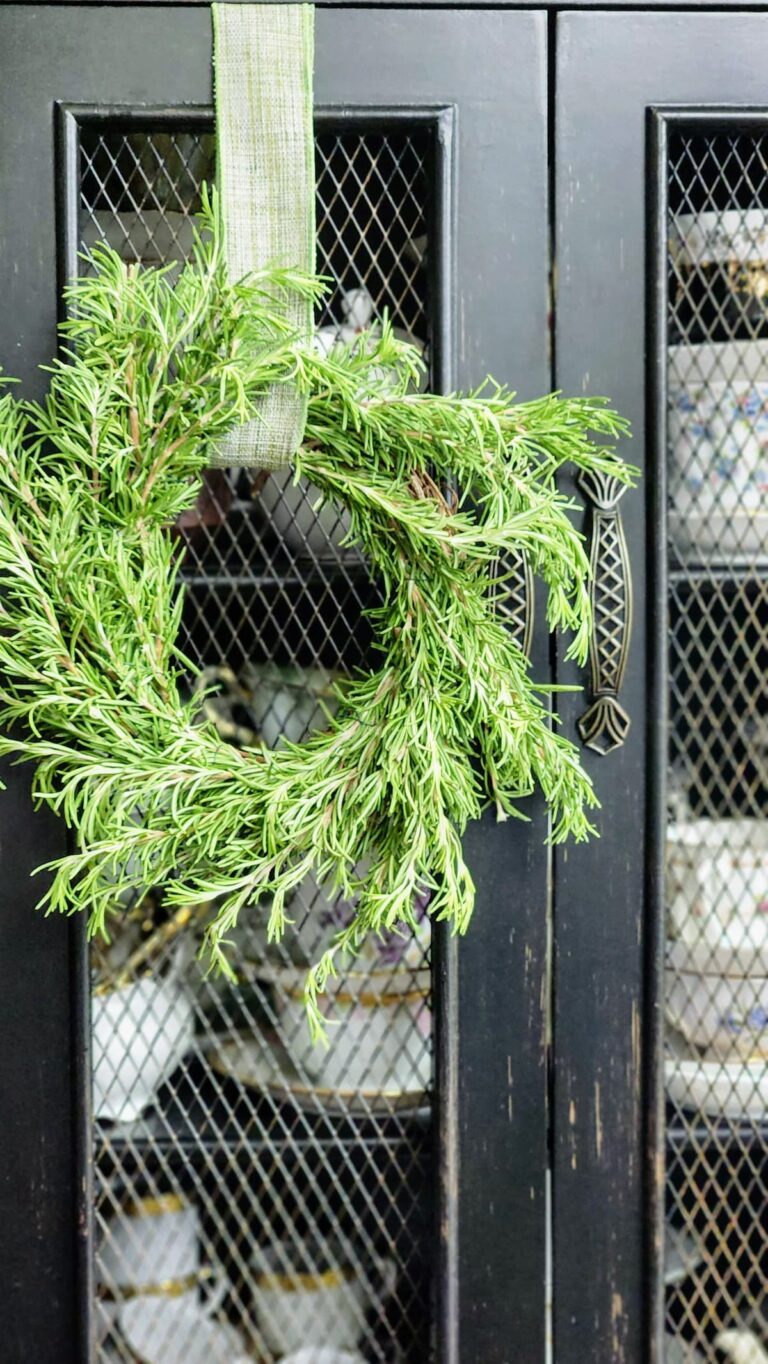 finished rosemary wreath hanging on black sideboard in kitchen