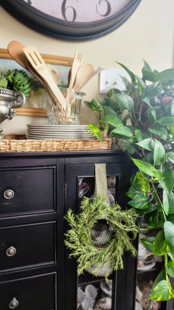 diy rosemary wreath hanging from ribbon on black sideboard in kitchen