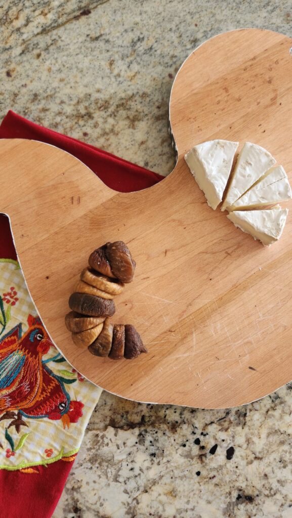 rooster wooden cutting board with dried figs and brie cheese on it