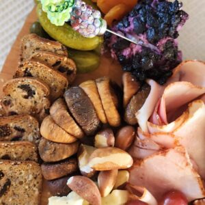 small charcuterie board with crackers, blueberry goat cheese, ham and brazil nuts