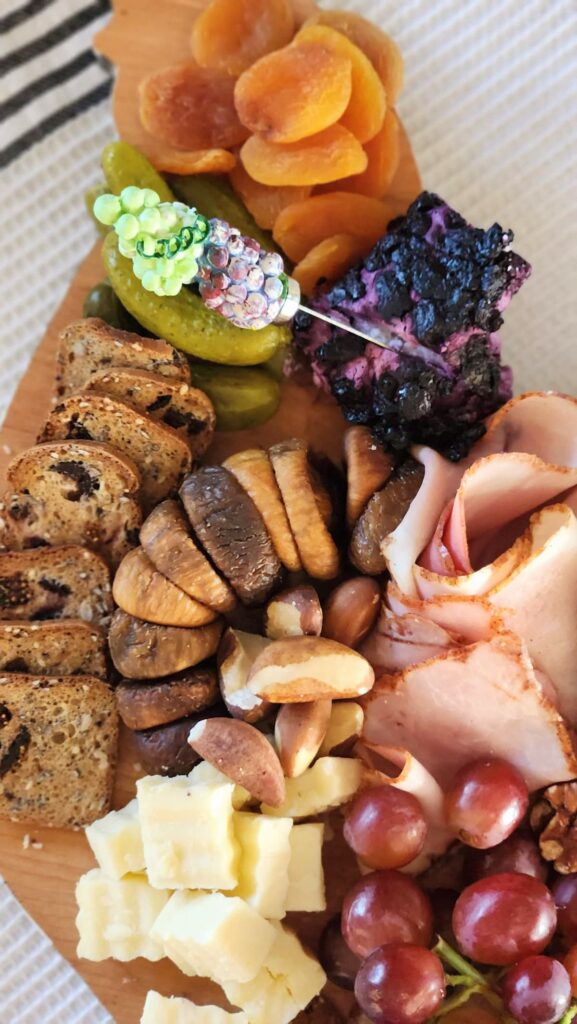 small charcuterie board with crackers, blueberry goat cheese, ham and brazil nuts