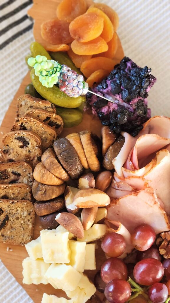 charcuterie board with dried figs, goat cheese, pickles and brazil nuts