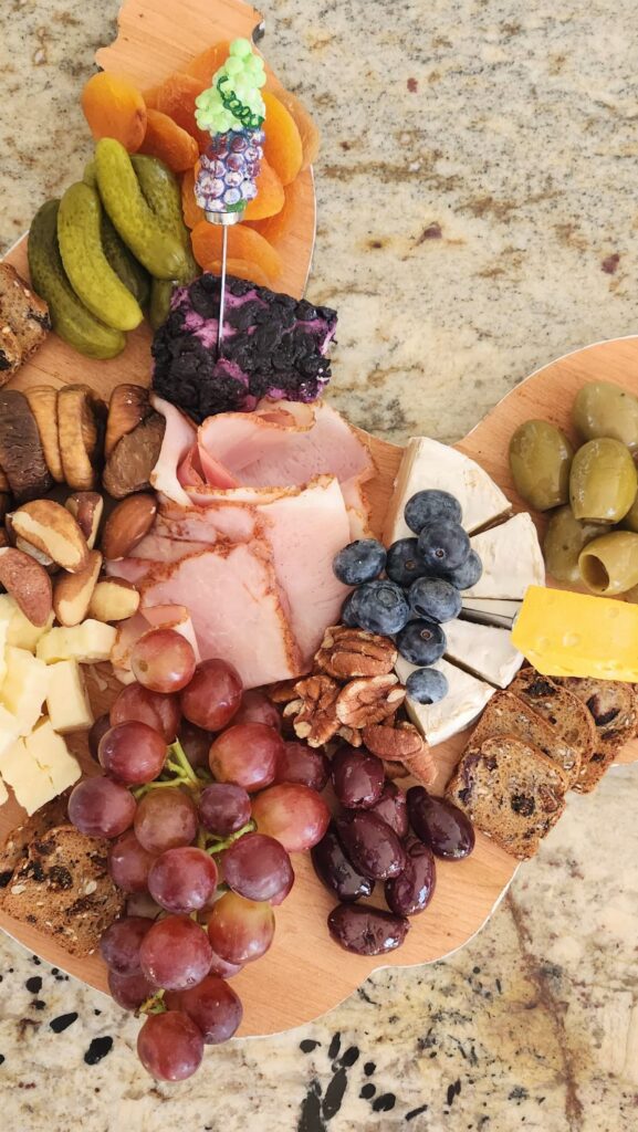 overhead of charcuterie board with fruit, nuts, olives, cheese, figs and pickles