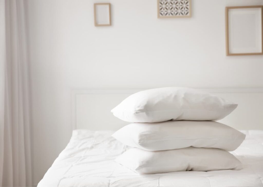 unmade mattress with three pillows on top of mattress