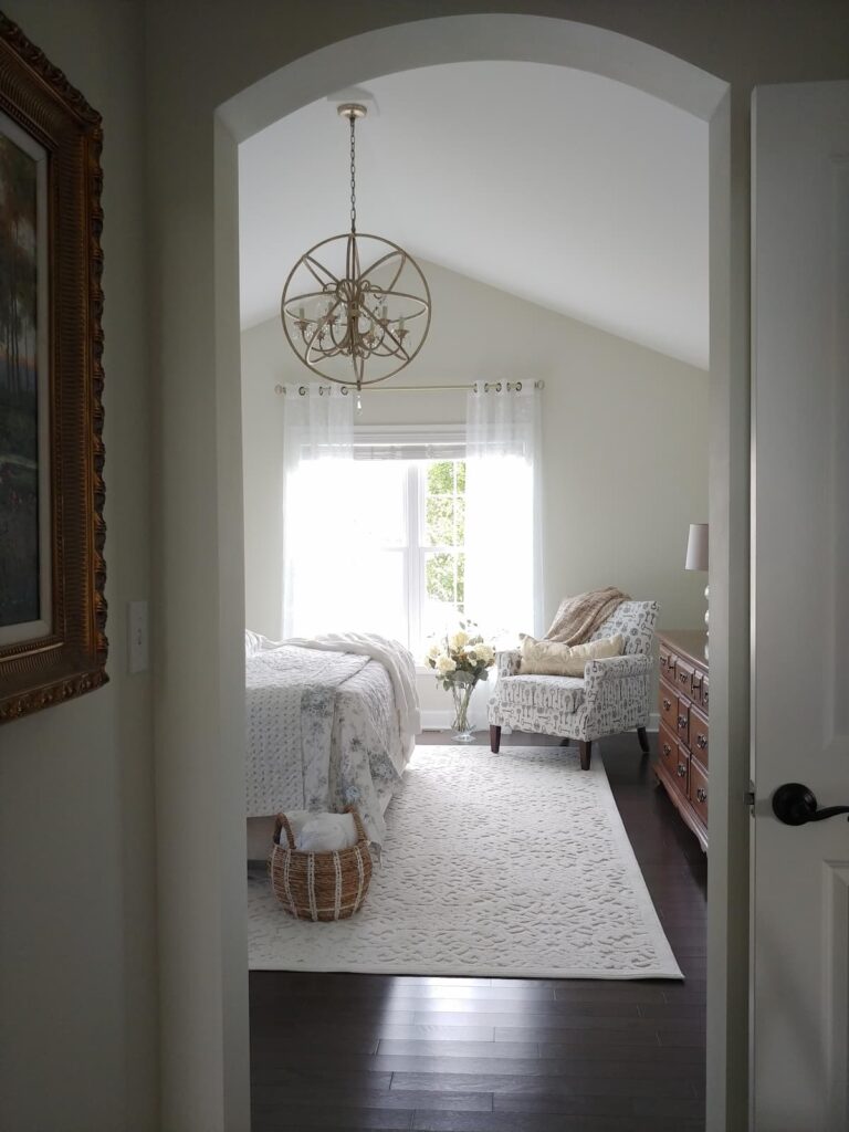 view of bedroom from door way with chandelier, chair and window in back 