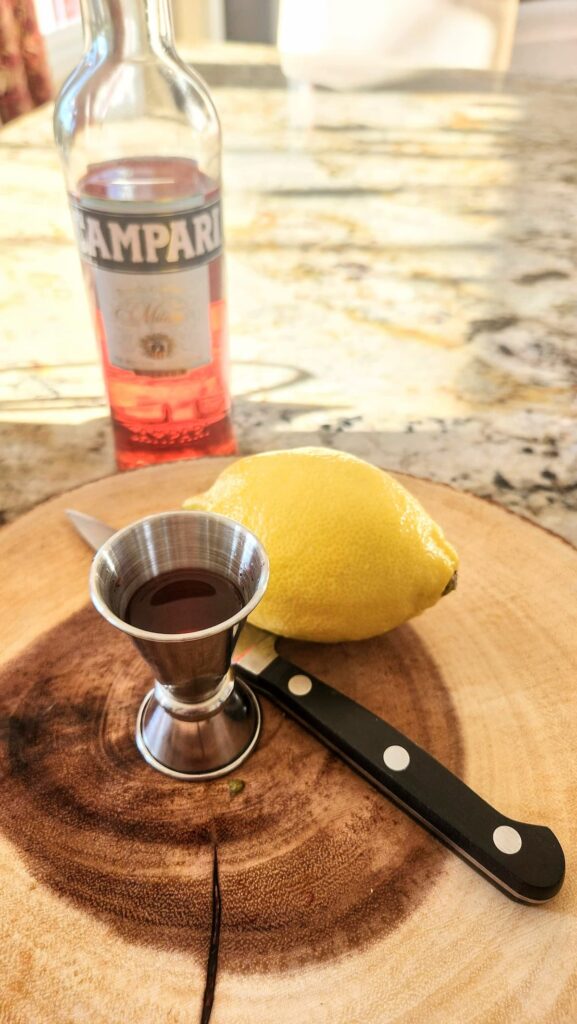 lemon with cocktail shot glass filled with campari liquer
