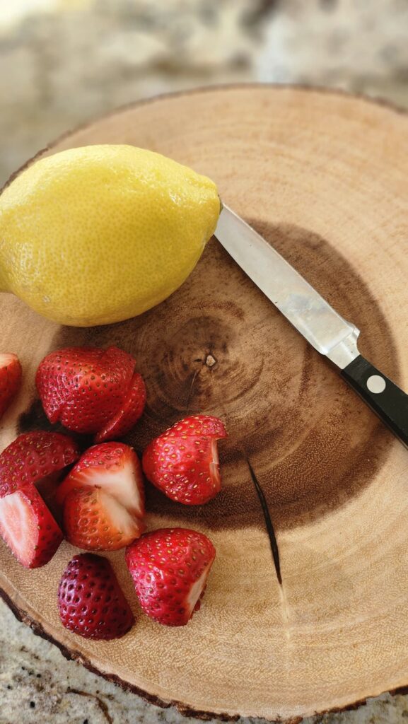 lemon and sliced strawberries on round wood cutting board
