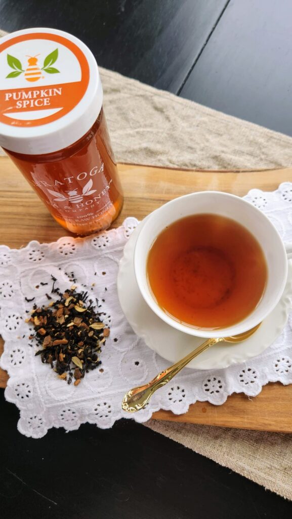 cup of pumpkin spice tea in white teacup with pumpkin spice jar of honey next to it