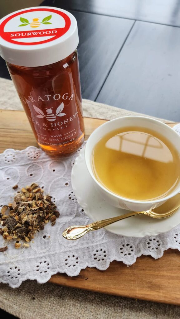 Songbird tea in white cup next to sourwood honey jar