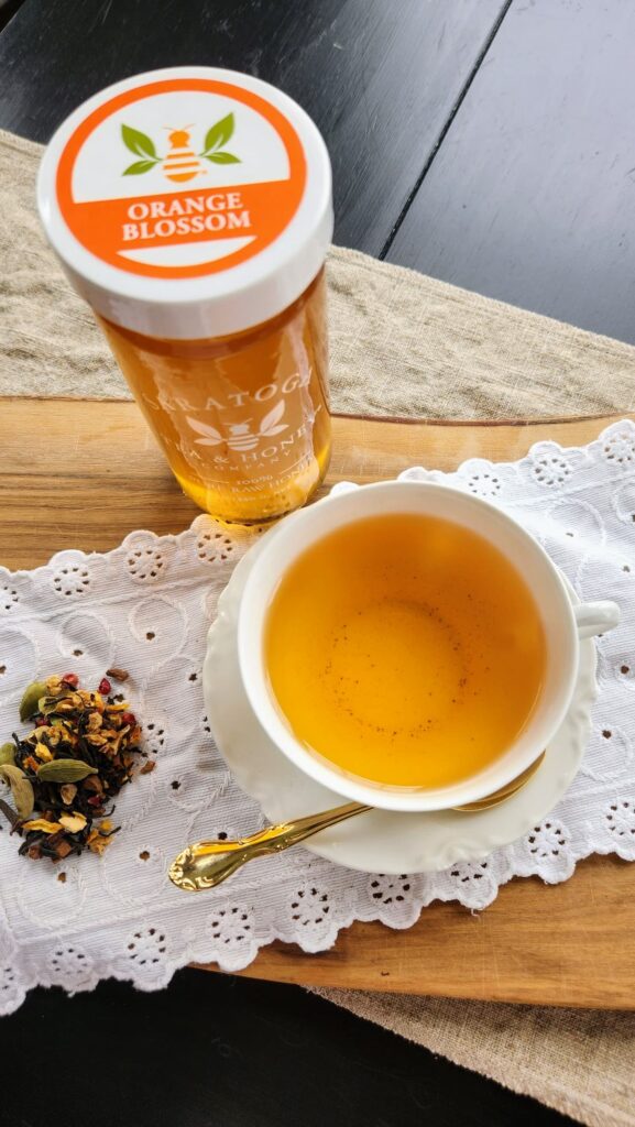 spiced orange Chai tea in cup with orange blossom jar of honey next to it