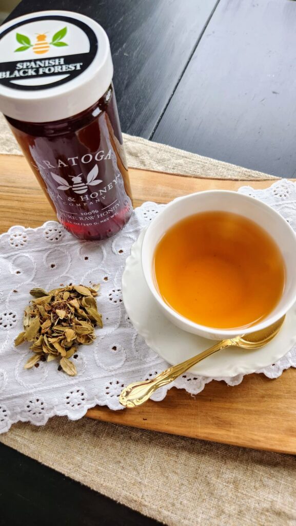 Saratoga red chai tea in white tea cup with spanish black forest honey jar next to it