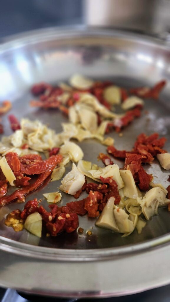 sundried tomatoes and artichokes sauteed in frying pan