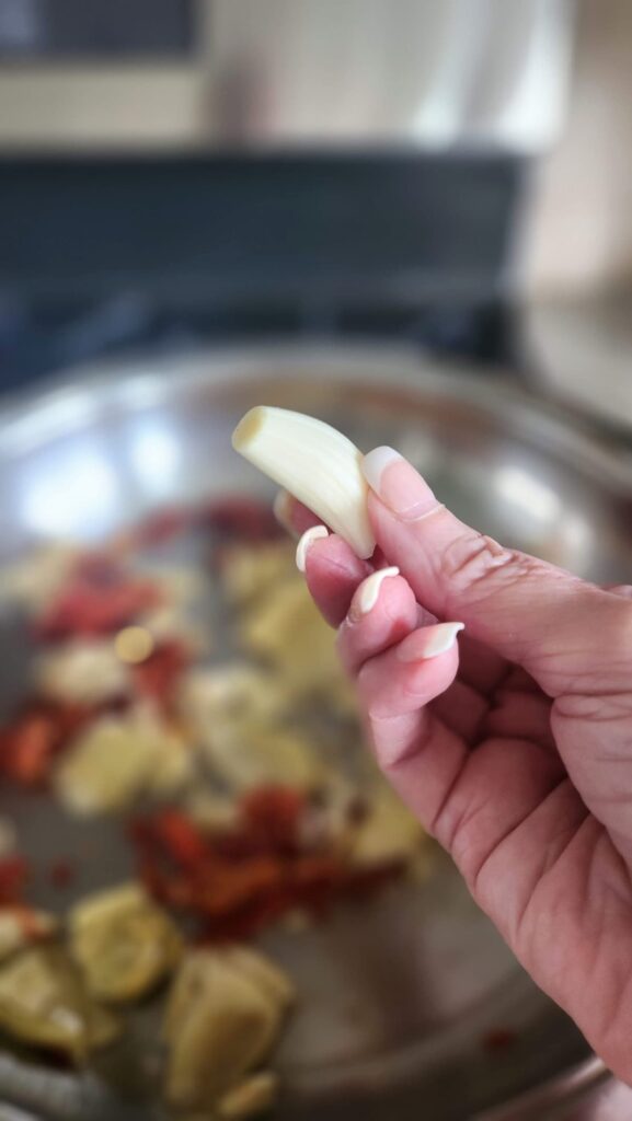 Garlic glove in hand over frying pan