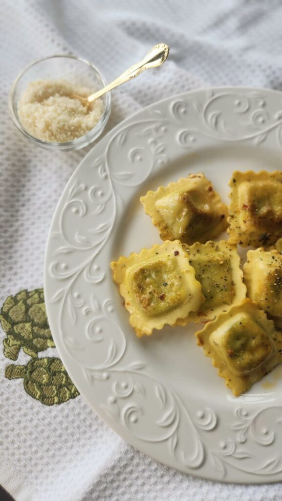 plate of sauteed ravioli with grated cheese on side, before sundried tomatoes are added