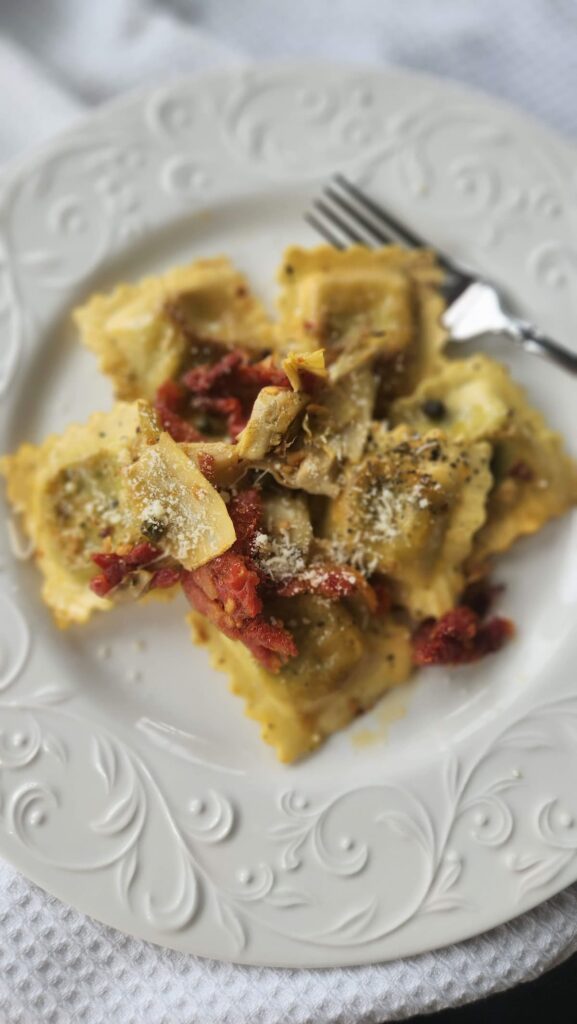sauteed ravioli on plate with sundried tomatoes, artichokes and capers